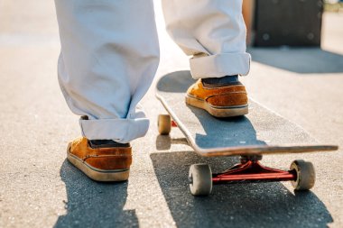 Kaykayın üstünde spor ayakkabılarla bacaklar.