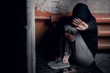 Uyuşturucu bağımlılığı ve evsizlik kavramı. Depresyonda ve umutsuz bir kadın terk edilmiş bir evde uyuşturucu ve alkol aldıktan sonra oturur..