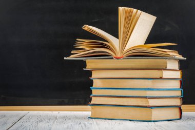 Tahtaya karşı beyaz bir masanın üzerinde bir yığın kitap.
