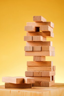 Jenga modeliyle girişimci riski kavramı. Sarı arka planda tahta bloklar