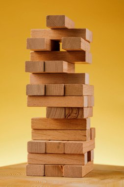 Jenga modeliyle girişimci riski kavramı. Sarı arka planda tahta bloklar