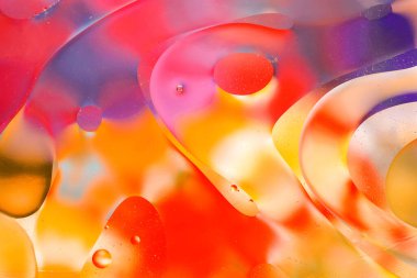 Su yüzeyindeki yağ damlacıklarının hareketine yakın çekim. Su yüzeyindeki yağ damlalarının renkli ve soyut makro arkaplanı