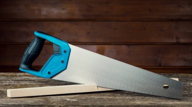 Yakın plan mavi saplı el testeresi. Tahta bir arka planda ağaç kesmek için el testeresi. Marangozluk için el aletleri