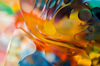 Su yüzeyindeki yağ damlacıklarının hareketine yakın çekim. Su yüzeyindeki yağ damlalarının renkli ve soyut makro arkaplanı