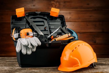 İnşaat kaskı ve çeşitli el aletleriyle plastik alet çantası aç.