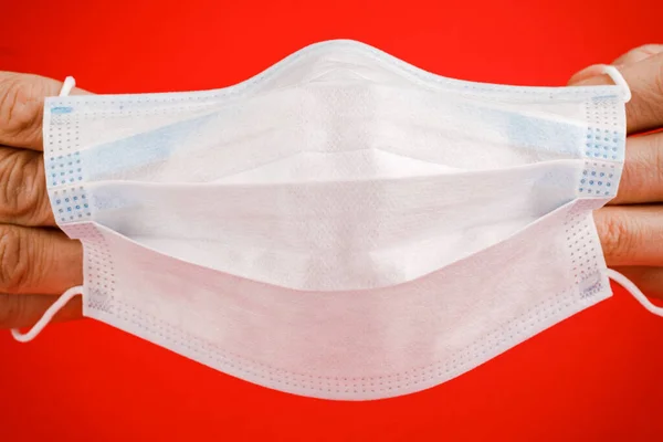 Medical mask, a medical protective mask isolated on a red background. A disposable surgical face mask covers the mouth and nose. Health care coronavirus medical quarantine, hygiene concept.