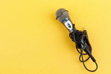 Sarı arka planda akustik mikrofon. Yukarıdan görünüşü.
