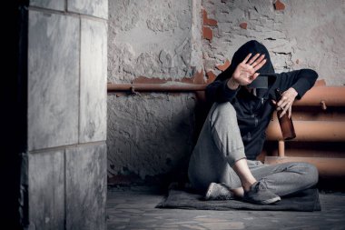 Uyuşturucu bağımlılığı ve evsizlik kavramı. Depresyonda ve umutsuz bir kadın terk edilmiş bir evde uyuşturucu ve alkol aldıktan sonra oturur..
