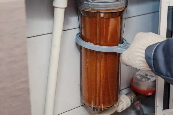 Water filtration - the plumber changes the dirty water filter. Cleaning of tap water.