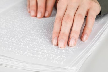 Bir kadın körler alfabesiyle yazılmış bir kitap okuyor.