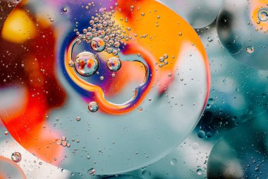 Su yüzeyindeki yağ damlacıklarının hareketine yakın çekim. Su yüzeyindeki yağ damlalarının renkli ve soyut makro arkaplanı