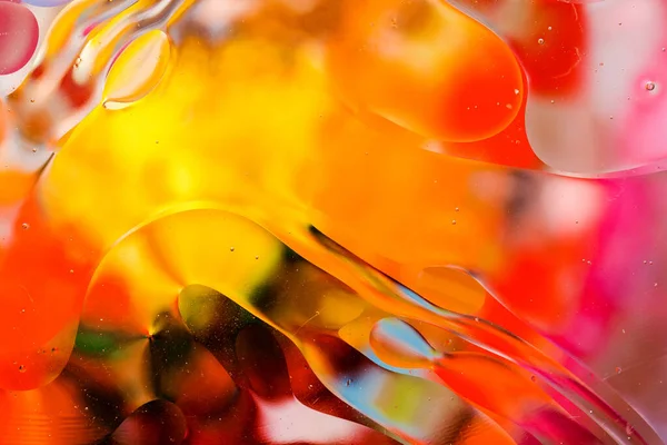 Su yüzeyindeki yağ damlacıklarının hareketine yakın çekim. Su yüzeyindeki yağ damlalarının renkli ve soyut makro arkaplanı