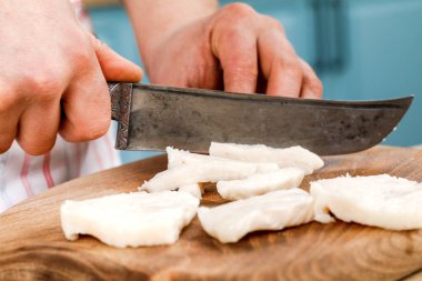 Aşçı çiğ domuz yağını tahta kesme tahtasıyla küçük parçalara ayırır.