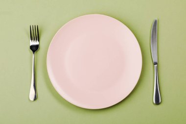 Yeşil arka planda bıçak, tabak ve çatal.