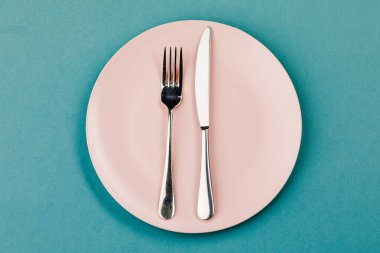 Yeşil arka planda bıçak, tabak ve çatal.