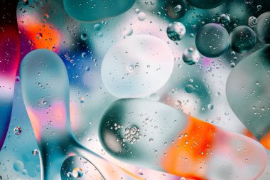 Su yüzeyindeki yağ damlacıklarının hareketine yakın çekim. Su yüzeyindeki yağ damlalarının renkli ve soyut makro arkaplanı