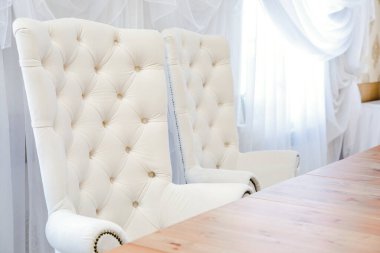 Tahta bir masanın yanında büyük sandalyeler.