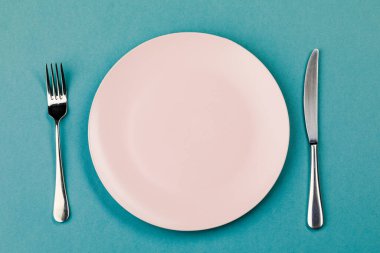 Yeşil arka planda bıçak, tabak ve çatal.