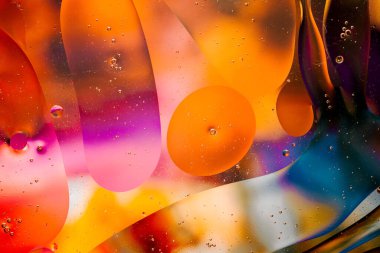 Su yüzeyindeki yağ damlacıklarının hareketine yakın çekim. Su yüzeyindeki yağ damlalarının renkli ve soyut makro arkaplanı