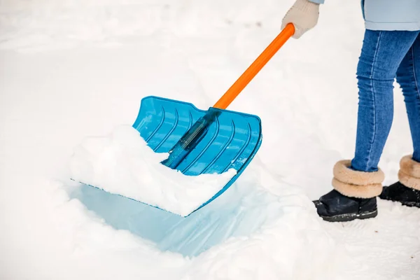 A person using a snow shovel cleans the road or playground from snow.