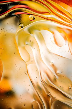 Su yüzeyindeki yağ damlacıklarının hareketine yakın çekim. Su yüzeyindeki yağ damlalarının renkli ve soyut makro arkaplanı