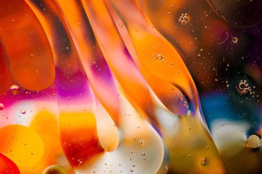 Su yüzeyindeki yağ damlacıklarının hareketine yakın çekim. Su yüzeyindeki yağ damlalarının renkli ve soyut makro arkaplanı