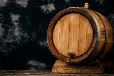 Güzel bir ahşap fıçı ve eskimiş meşe ağacından bir masa tasarlamak için karanlık bir duvar desenine karşı dizilmiş..