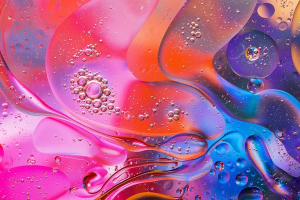 Close-up of the movement of oil droplets on the water surface. Colorful abstract macro background of oil drops on the water surface