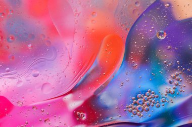 Su yüzeyindeki yağ damlacıklarının hareketine yakın çekim. Su yüzeyindeki yağ damlalarının renkli ve soyut makro arkaplanı