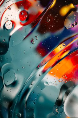 Su yüzeyindeki yağ damlacıklarının hareketine yakın çekim. Su yüzeyindeki yağ damlalarının renkli ve soyut makro arkaplanı