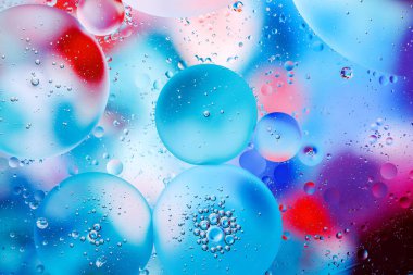 Su yüzeyindeki yağ damlacıklarının hareketine yakın çekim. Su yüzeyindeki yağ damlalarının renkli ve soyut makro arkaplanı