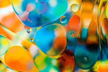 Su yüzeyindeki yağ damlacıklarının hareketine yakın çekim. Su yüzeyindeki yağ damlalarının renkli ve soyut makro arkaplanı