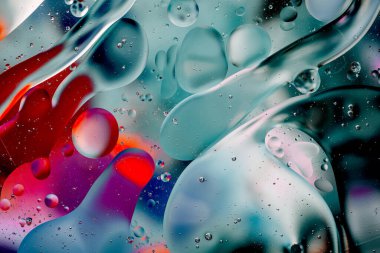 Su yüzeyindeki yağ damlacıklarının hareketine yakın çekim. Su yüzeyindeki yağ damlalarının renkli ve soyut makro arkaplanı