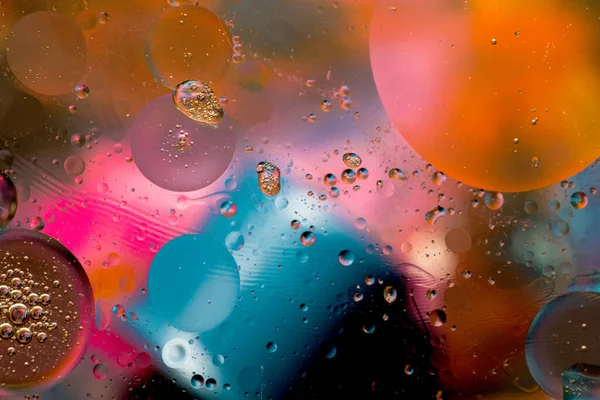 Close-up of the movement of oil droplets on the water surface. Colorful abstract macro background of oil drops on the water surface