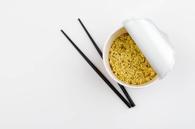 Beyaz arkaplanda yemek çubukları olan pakette hazır erişte..