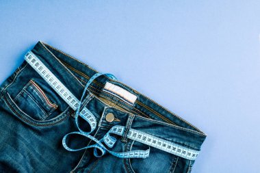 Sağlıklı yaşam tarzı ve diyet kavramı. Kemer yerine mavi ölçü bandıyla mavi kot pantolon..