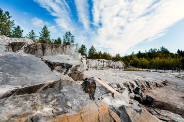 Kaya, doğal bir ortamda işlenmemiş beyaz ve gri mermerden bir yüzey oymuş. Mavi mermerin taş ocağı dokusu
