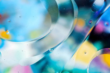 Su yüzeyindeki yağ damlacıklarının hareketine yakın çekim. Su yüzeyindeki yağ damlalarının renkli ve soyut makro arkaplanı