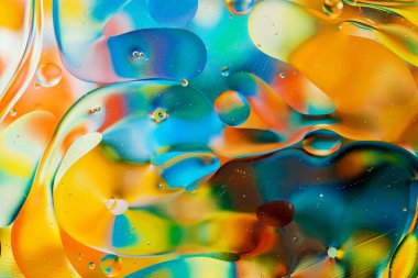 Su yüzeyindeki yağ damlacıklarının hareketine yakın çekim. Su yüzeyindeki yağ damlalarının renkli ve soyut makro arkaplanı