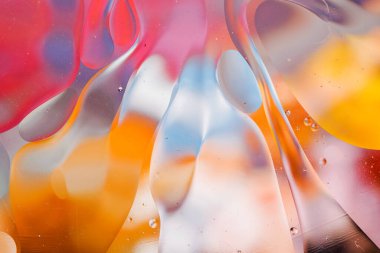 Su yüzeyindeki yağ damlacıklarının hareketine yakın çekim. Su yüzeyindeki yağ damlalarının renkli ve soyut makro arkaplanı