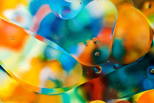 Close-up of the movement of oil droplets on the water surface. Colorful abstract macro background of oil drops on the water surface