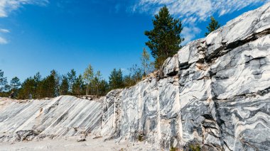 Kaya, doğal bir ortamda işlenmemiş beyaz ve gri mermerden bir yüzey oymuş. Mavi mermerin taş ocağı dokusu