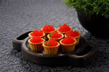 Siyah arka planda kırmızı havyarlı iştah açıcı tartlar. Tatil kavramı.