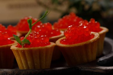Dekoratif panoda servis için kırmızı havyarlı iştah açıcı tartlar. Tatil kavramı.