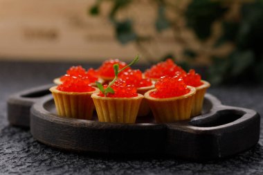 Dekoratif panoda servis için kırmızı havyarlı iştah açıcı tartlar. Tatil kavramı.