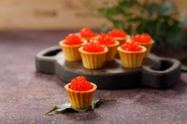 Dekoratif panoda servis için kırmızı havyarlı iştah açıcı tartlar. Tatil kavramı.