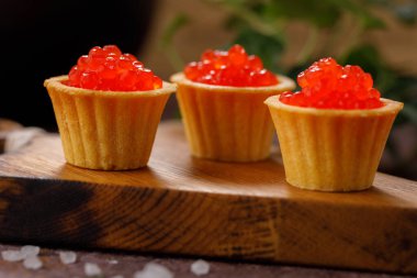 Dekoratif panoda servis için kırmızı havyarlı iştah açıcı tartlar. Tatil kavramı.