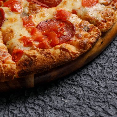 Siyah desenli arka planda Pepperoni pizza. İtalyan yemeği konsepti. Yakın plan..