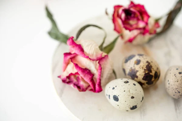 Still life with roses. Quail eggs on a wooden stand. Rustic.