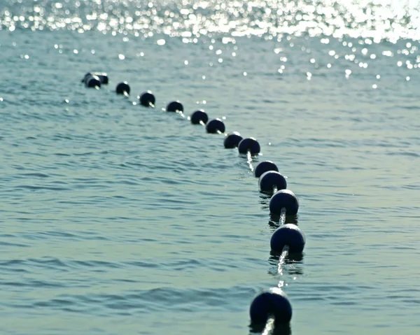 Boe appese insieme su belle acque azzurre scintillanti al mattino presto. Boe di sicurezza per creare una zona di nuoto sicura per i nuotatori — Foto Stock